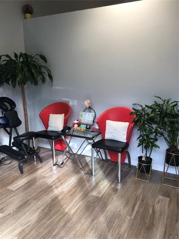 A waiting area features two red chairs, a glass table, and several potted plants — 3370 ROUSE ROAD UNIT 117, ORLANDO, FL