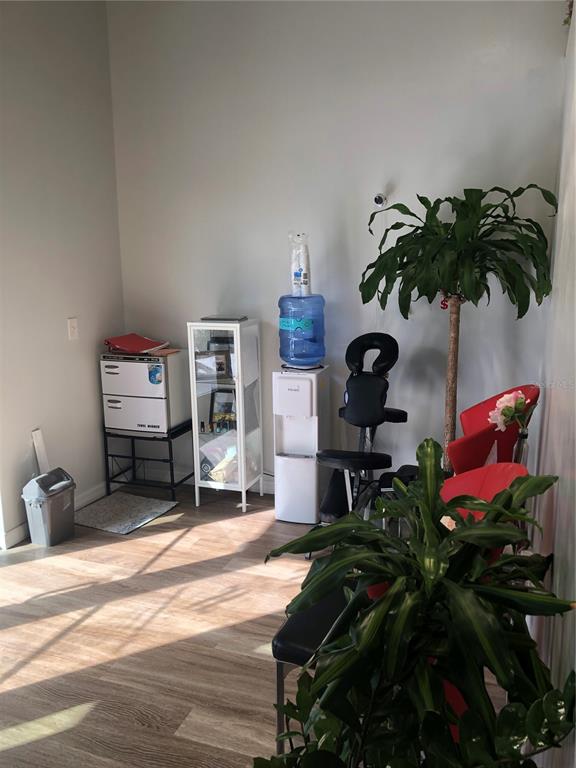 A room features light wood-look flooring, a water cooler, a massage chair, and potted plants — 3370 ROUSE ROAD UNIT 117, ORLANDO, FL