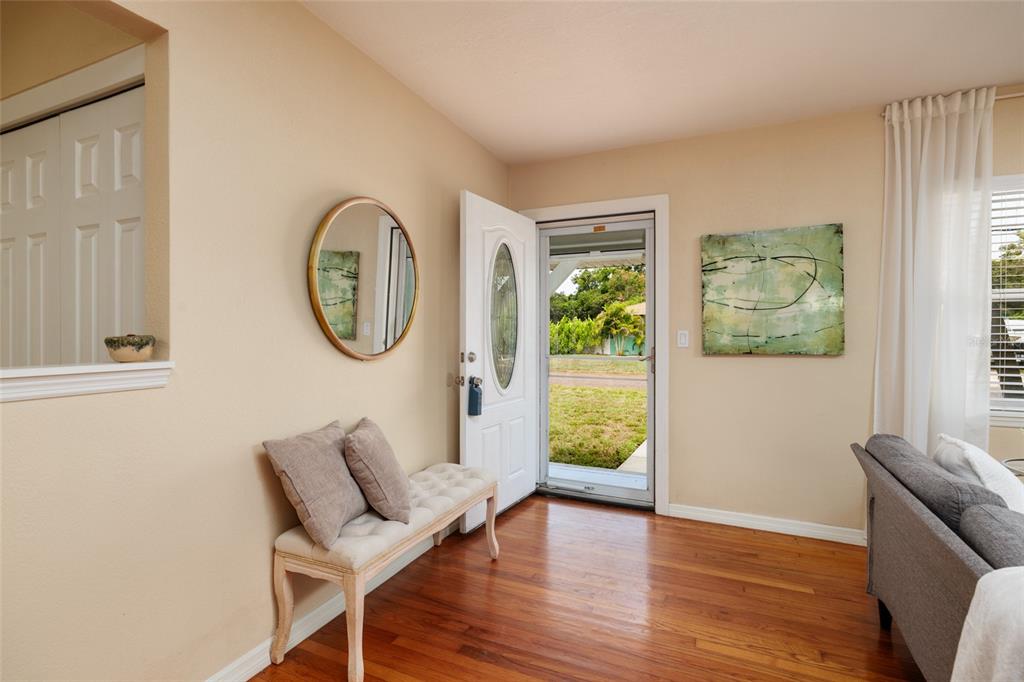 An entryway features a wooden bench, a round mirror, and an open door to outside — 801 61ST STREET N, ST PETERSBURG, FL