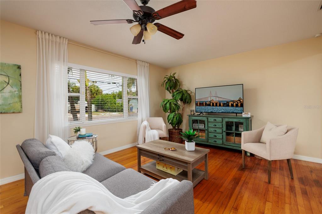 A living room features hardwood floors, a gray sofa, two armchairs, and a television console — 801 61ST STREET N, ST PETERSBURG, FL