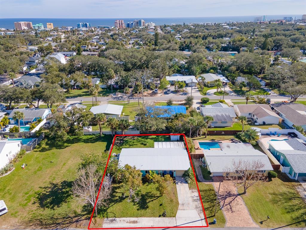 An aerial view shows a single-story house with a metal roof and a concrete driveway — 617 GOODWIN AVENUE, NEW SMYRNA BEACH, FL