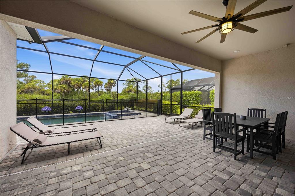 A covered patio features a dining set, lounge chairs, a pool, and a screened enclosure — 17365 JADESTONE COURT, VENICE, FL