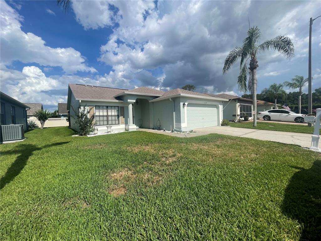 A single-story house with a light-colored exterior, a two-car garage, and a palm tree — 13104 BARTH PLACE UNIT 13104, RIVERVIEW, FL