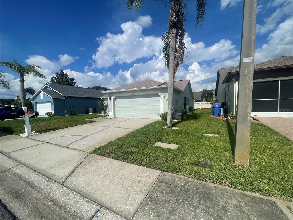 A single-story house with a light-colored exterior, a two-car garage, and a palm tree — 13104 BARTH PLACE UNIT 13104, RIVERVIEW, FL