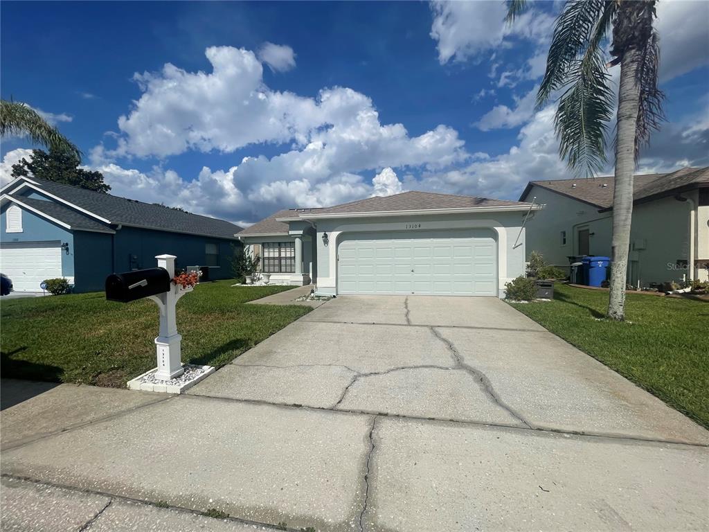 A single-story house with a light-colored facade, a two-car garage, and a cracked concrete driveway — 13104 BARTH PLACE UNIT 13104, RIVERVIEW, FL