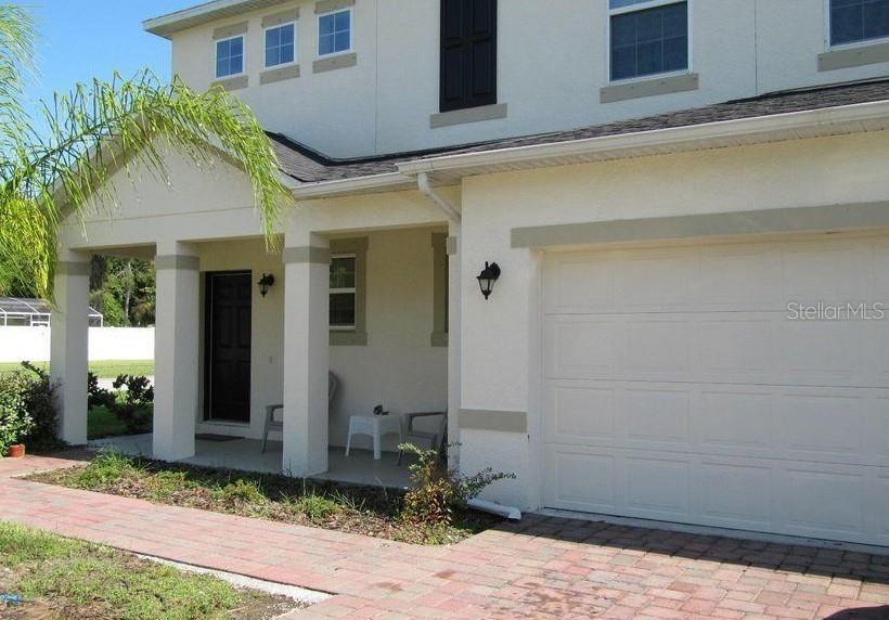 A two-story house exterior features a covered front porch, a garage, and a brick walkway — 3938 SUNSET COVE DRIVE, PORT ORANGE, FL