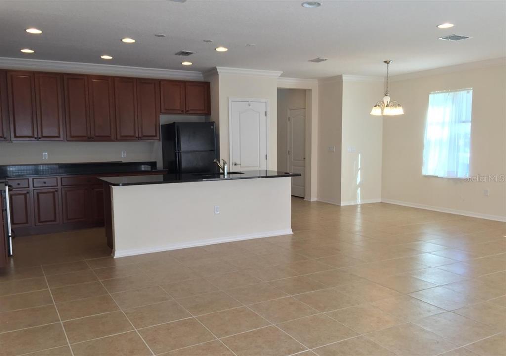 A kitchen with dark wood cabinets, black countertops, and a breakfast bar island — 3938 SUNSET COVE DRIVE, PORT ORANGE, FL