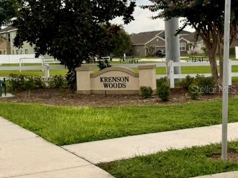 A stone monument sign for Krenson Woods stands in a grassy neighborhood entrance — 811 KRENSON WOODS LANE, LAKELAND, FL
