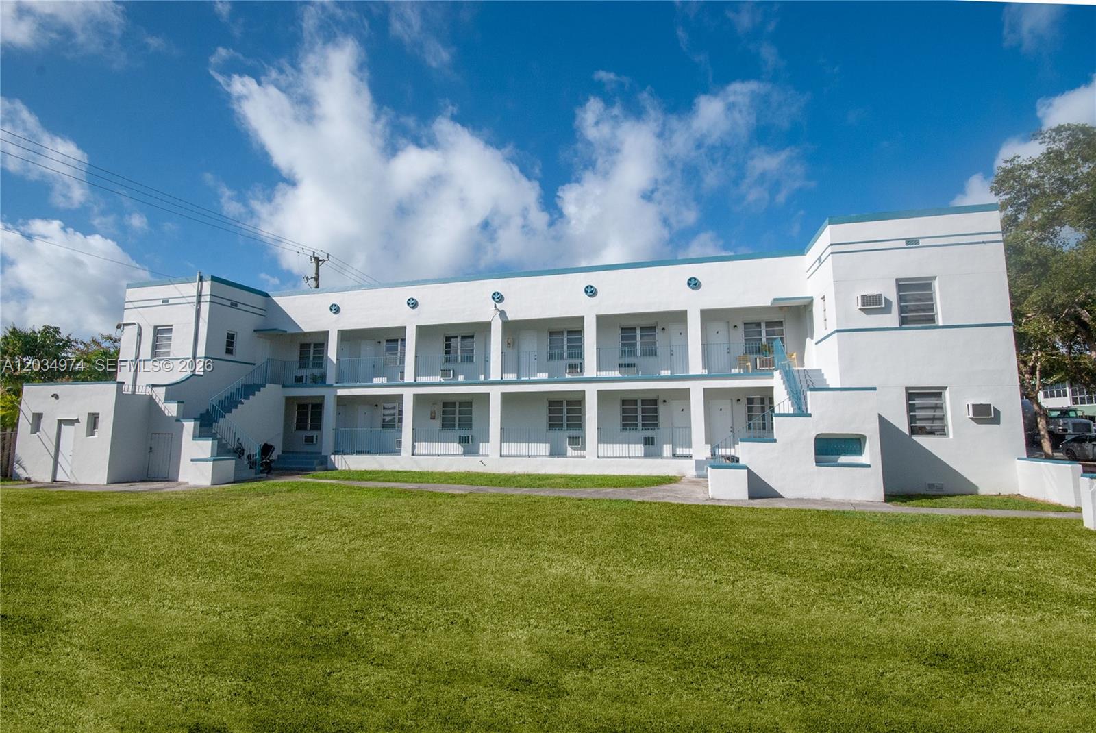 A two-story white apartment building with blue trim features exterior staircases and open walkways — 1208 71st St # 3, Miami Beach FL 33141, MIAMI BEACH, FL