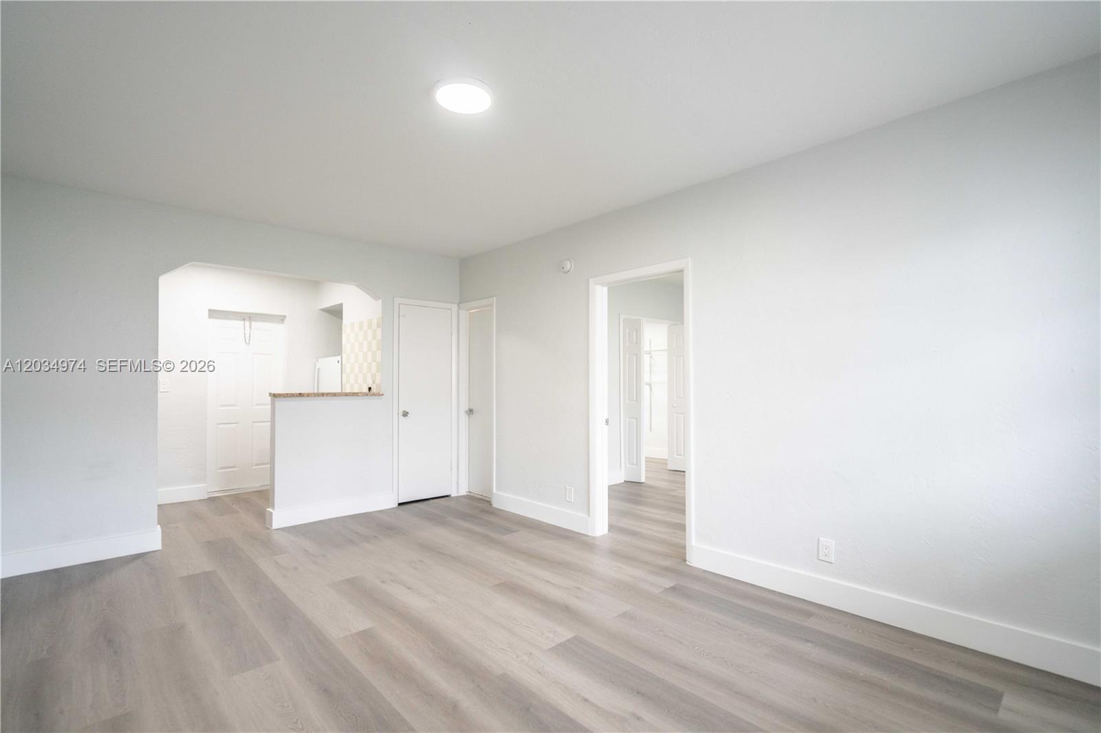 An interior view shows a living area with light-colored walls, wood-look flooring, and doorways — 1208 71st St # 3, Miami Beach FL 33141, MIAMI BEACH, FL