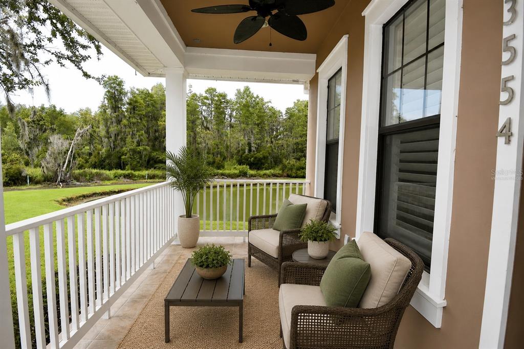A covered porch features wicker chairs, a coffee table, and a view of a pond — 3554 PICKERELL PLACE, NEW PORT RICHEY, FL