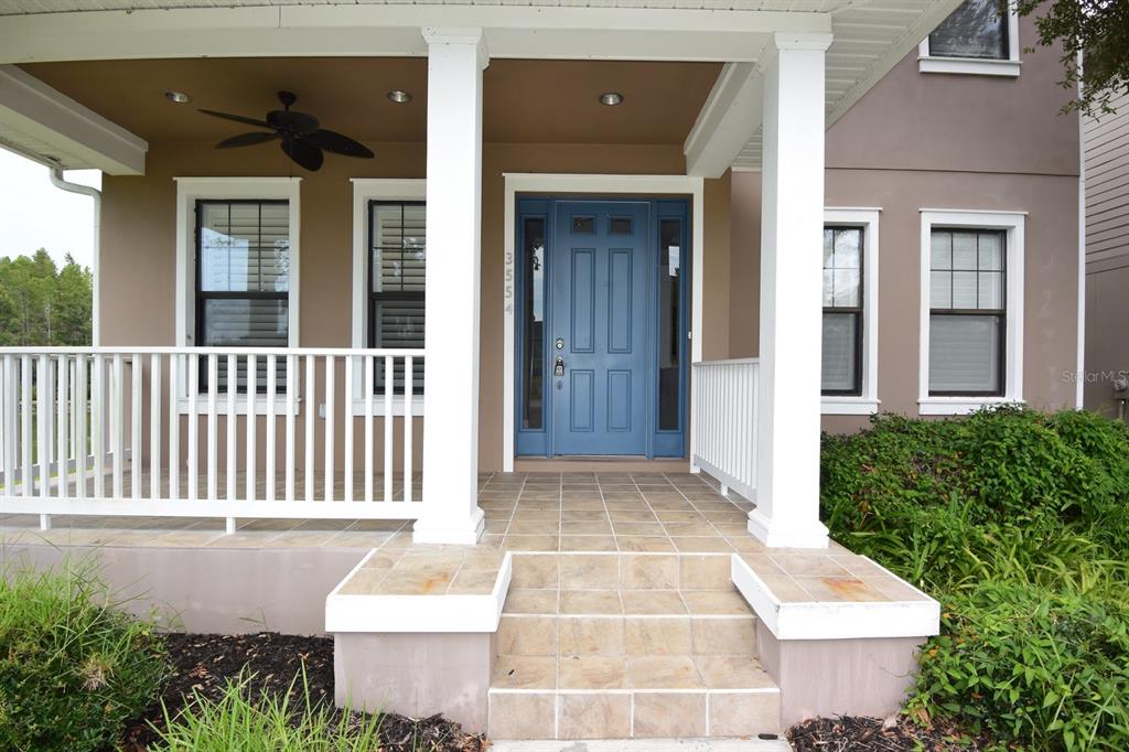 A front porch with a blue door, white railings, and tiled steps leads to a house — 3554 PICKERELL PLACE, NEW PORT RICHEY, FL