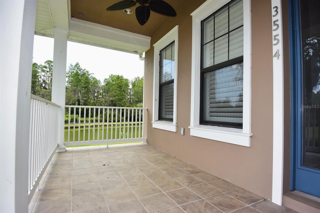 A covered porch features tiled flooring, a ceiling fan, and a view of a pond — 3554 PICKERELL PLACE, NEW PORT RICHEY, FL