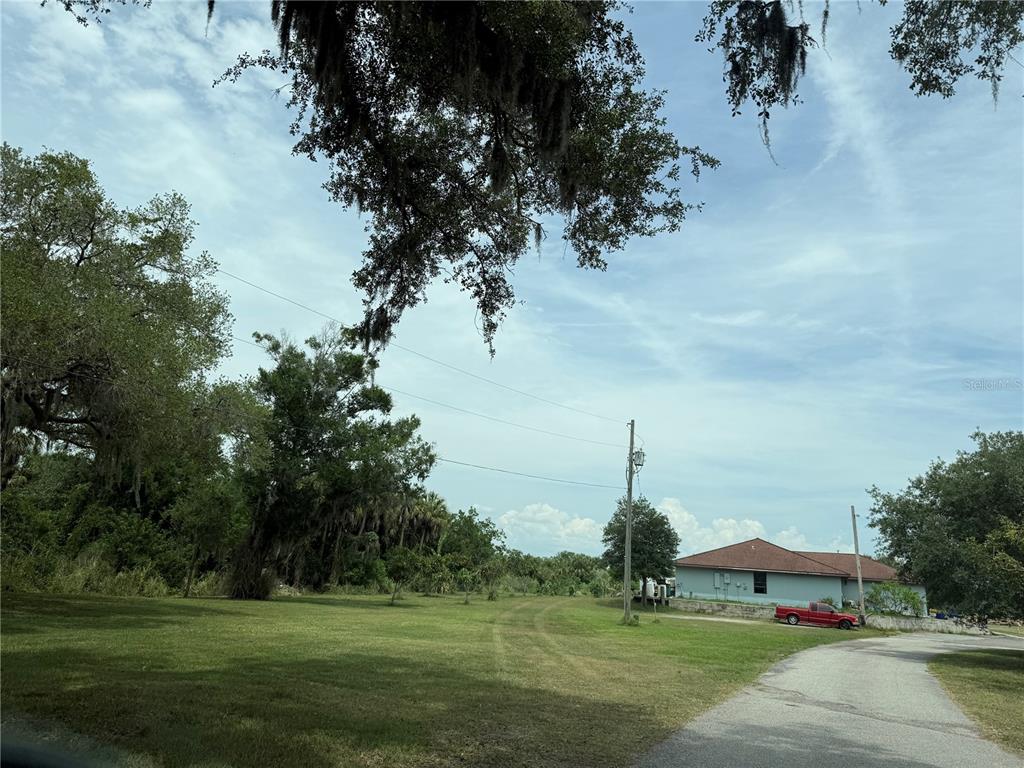 A grassy lot with scattered trees and a paved driveway leading toward a house — 3208 16TH AVE E, PALMETTO, FL