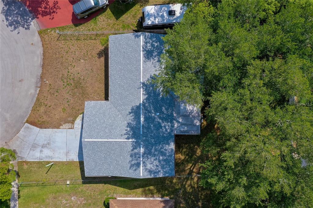 An aerial view shows a house with a gray shingled roof, driveway, and surrounding trees — 667 GEORGE MILLER CIRCLE, PORT ORANGE, FL