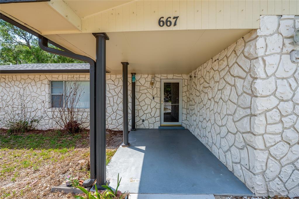 A covered front porch with a concrete floor and white stone exterior walls — 667 GEORGE MILLER CIRCLE, PORT ORANGE, FL
