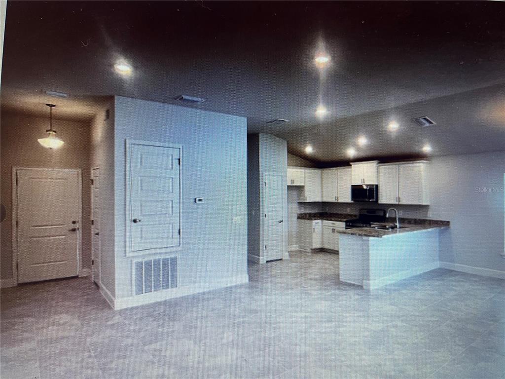 An open-concept kitchen with white cabinets, granite countertops, and tile flooring — 16253 SE 83RD COURT, SUMMERFIELD, FL
