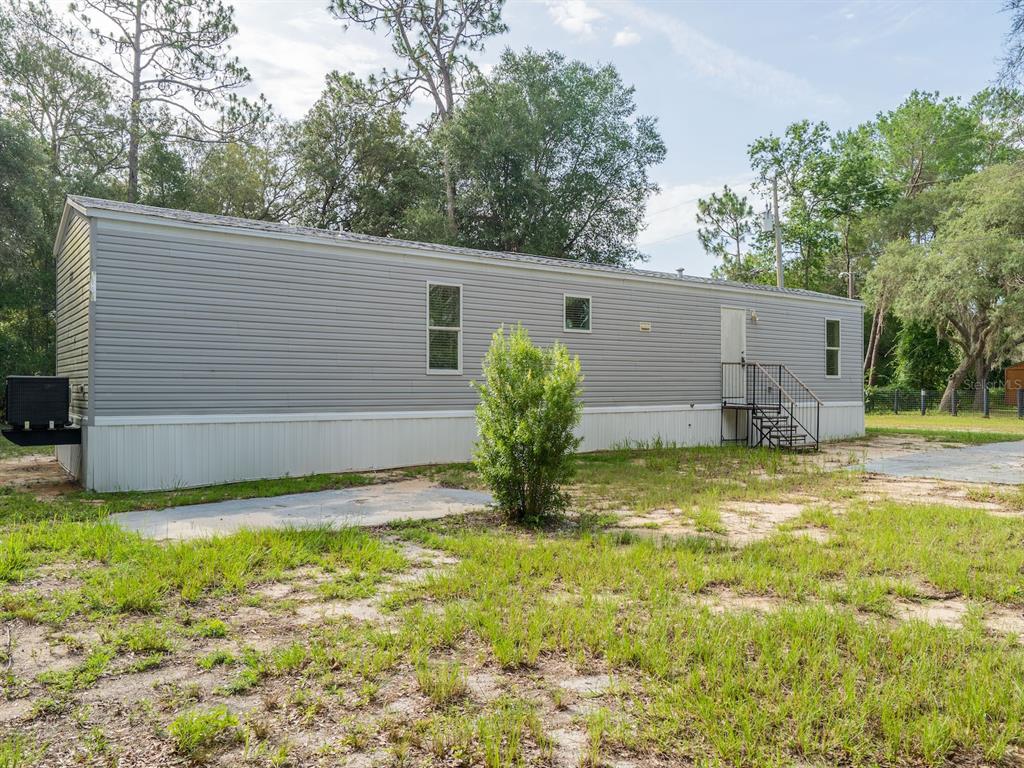 A single-story manufactured home with gray siding sits on a lot with sparse grass — 14585 NE 149TH LANE, FORT MC COY, FL
