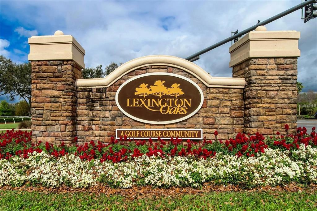 A stone monument sign for Lexington Oaks stands behind a bed of red and white flowers — 25638 FERDINAND COURT, WESLEY CHAPEL, FL
