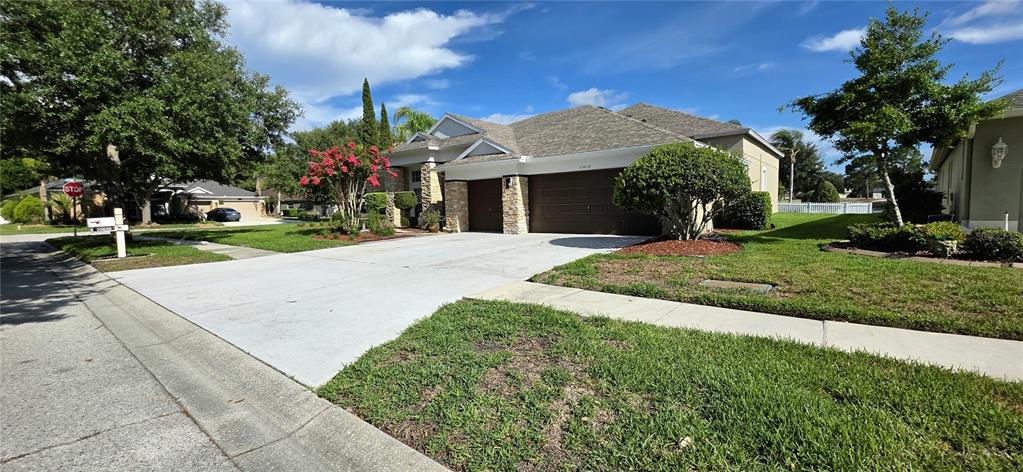 A single-story house with a stone facade, a concrete driveway, and a two-car garage — 25638 FERDINAND COURT, WESLEY CHAPEL, FL