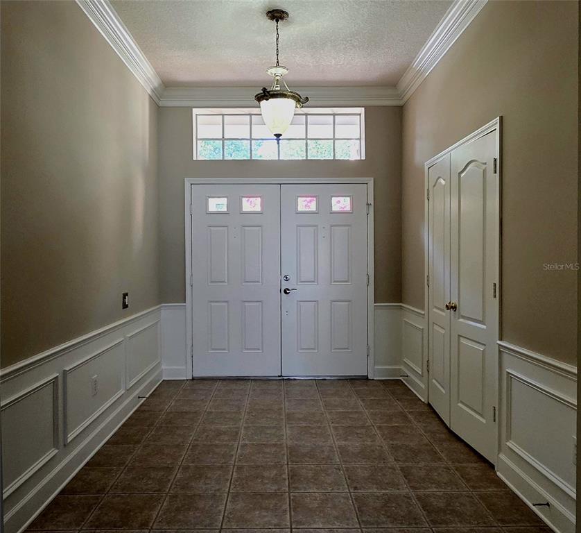 An entryway features double front doors, a transom window, tile flooring, and white wainscoting — 25638 FERDINAND COURT, WESLEY CHAPEL, FL