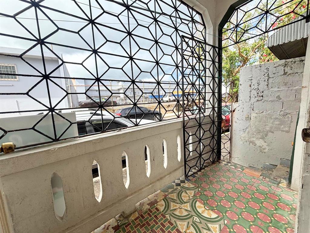 A covered porch features patterned tile flooring, a concrete half-wall, and decorative metal security grilles — 167 CALLE DEL PARQUE, SAN JUAN, PR