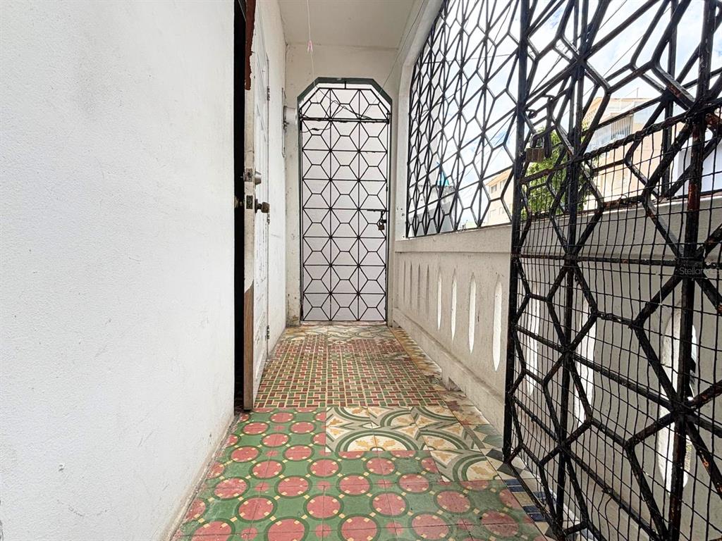 A narrow balcony features patterned tile flooring, white walls, and black metal security grilles — 167 CALLE DEL PARQUE, SAN JUAN, PR