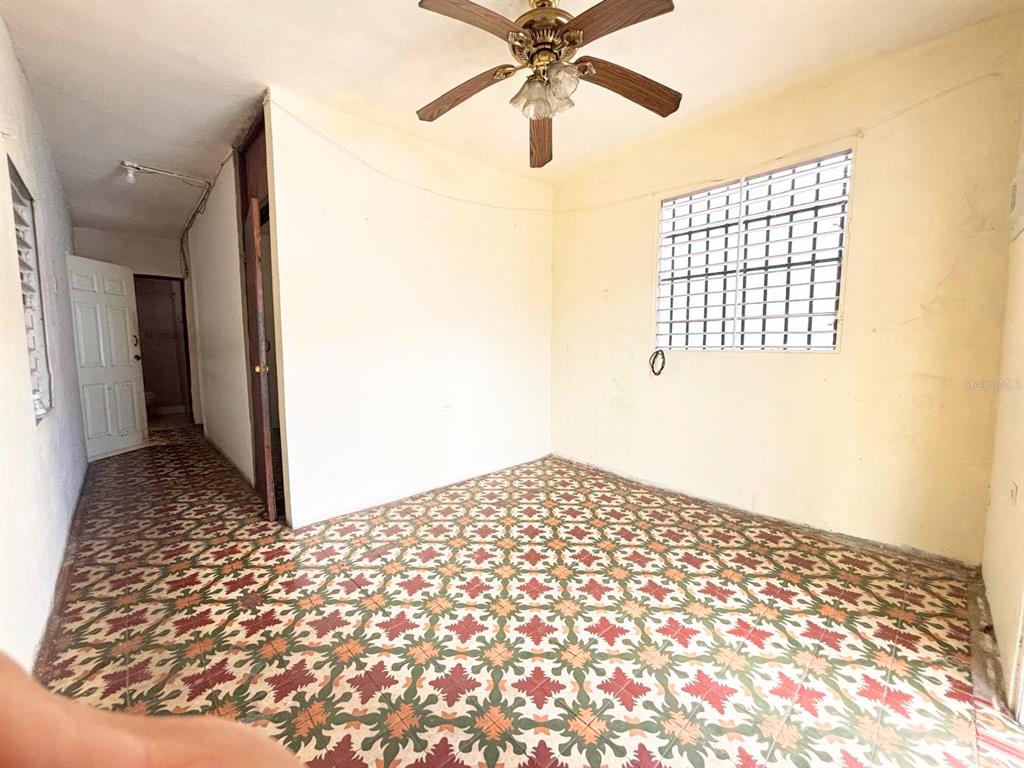 An empty room features patterned tile flooring, a ceiling fan, and a window with bars — 167 CALLE DEL PARQUE, SAN JUAN, PR