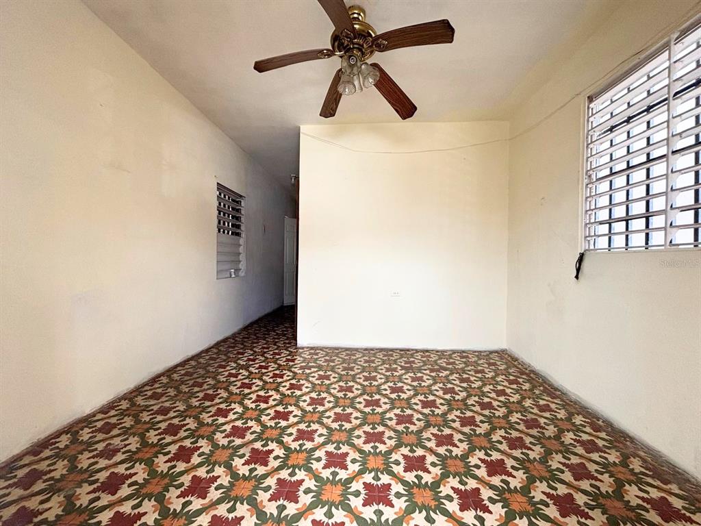 An empty room features a patterned tile floor, a ceiling fan, and a window with security bars — 167 CALLE DEL PARQUE, SAN JUAN, PR