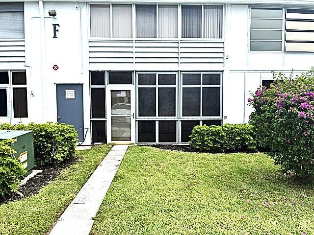 A white two-story building features a ground-level entrance, large windows, and a landscaped lawn — 110 Markham F # 110, Deerfield Beach FL 33442, DEERFIELD BEACH, FL