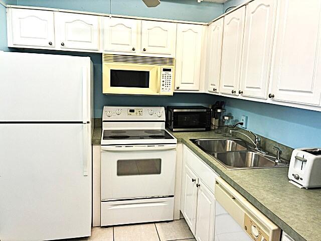 A kitchen features white cabinets, a white refrigerator, a white stove, and a double sink — 110 Markham F # 110, Deerfield Beach FL 33442, DEERFIELD BEACH, FL