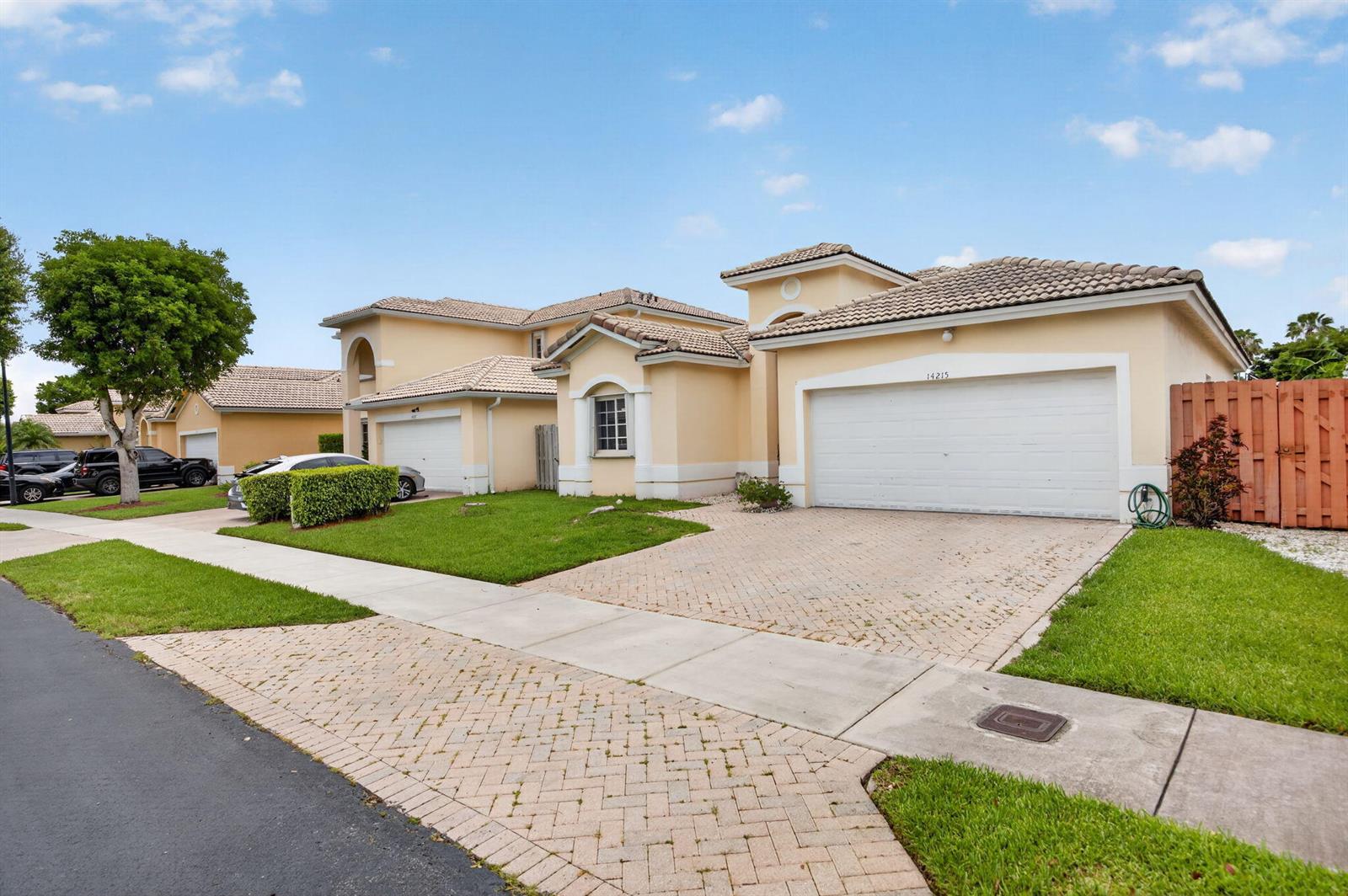 A tan stucco house with a tiled roof and a paved driveway under a blue sky — 14215 SW 156th Avenue N, Miami FL 33196, MIAMI, FL