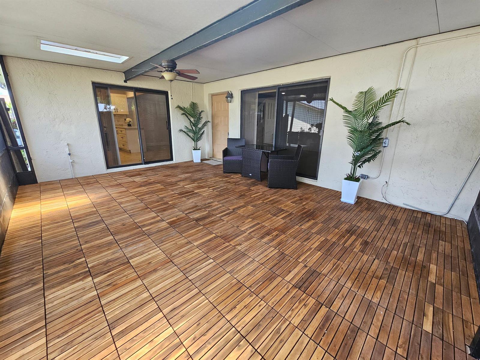 A covered patio features wood-look deck tiles, two potted plants, and a small bistro set — 717 NW 29th Avenue # B, Delray Beach FL 33445, DELRAY BEACH, FL