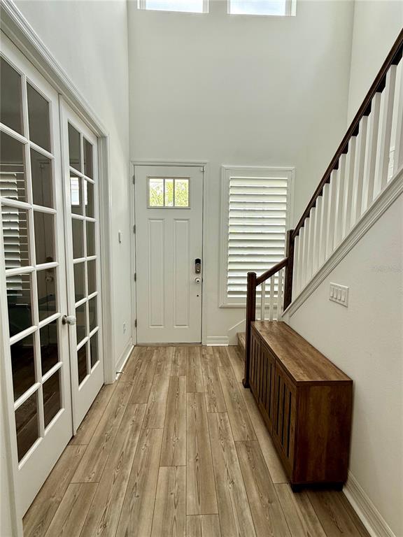 A bright entryway features wood-look flooring, a white front door, and a wooden console table — 1858 TREASURE COVE, CELEBRATION, FL