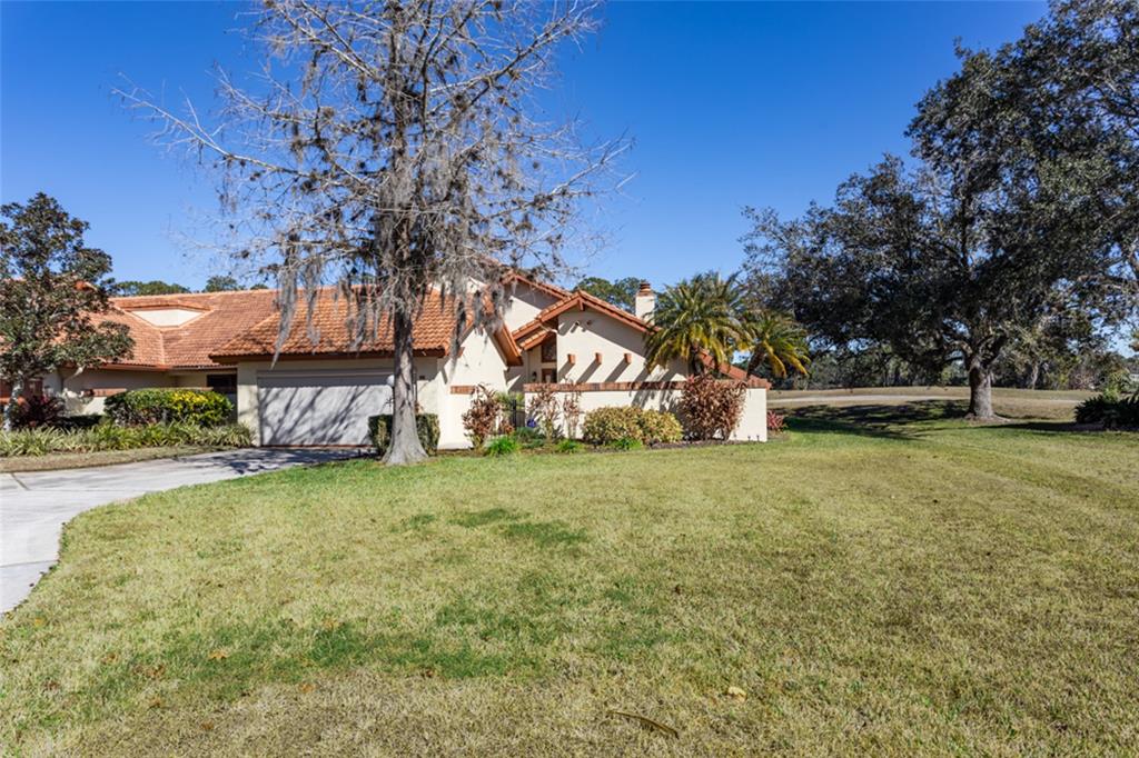 A single-story house with a tile roof, garage, and large front lawn under a blue sky — 39 VILLAGE CIRCLE UNIT 5-501, PALM COAST, FL