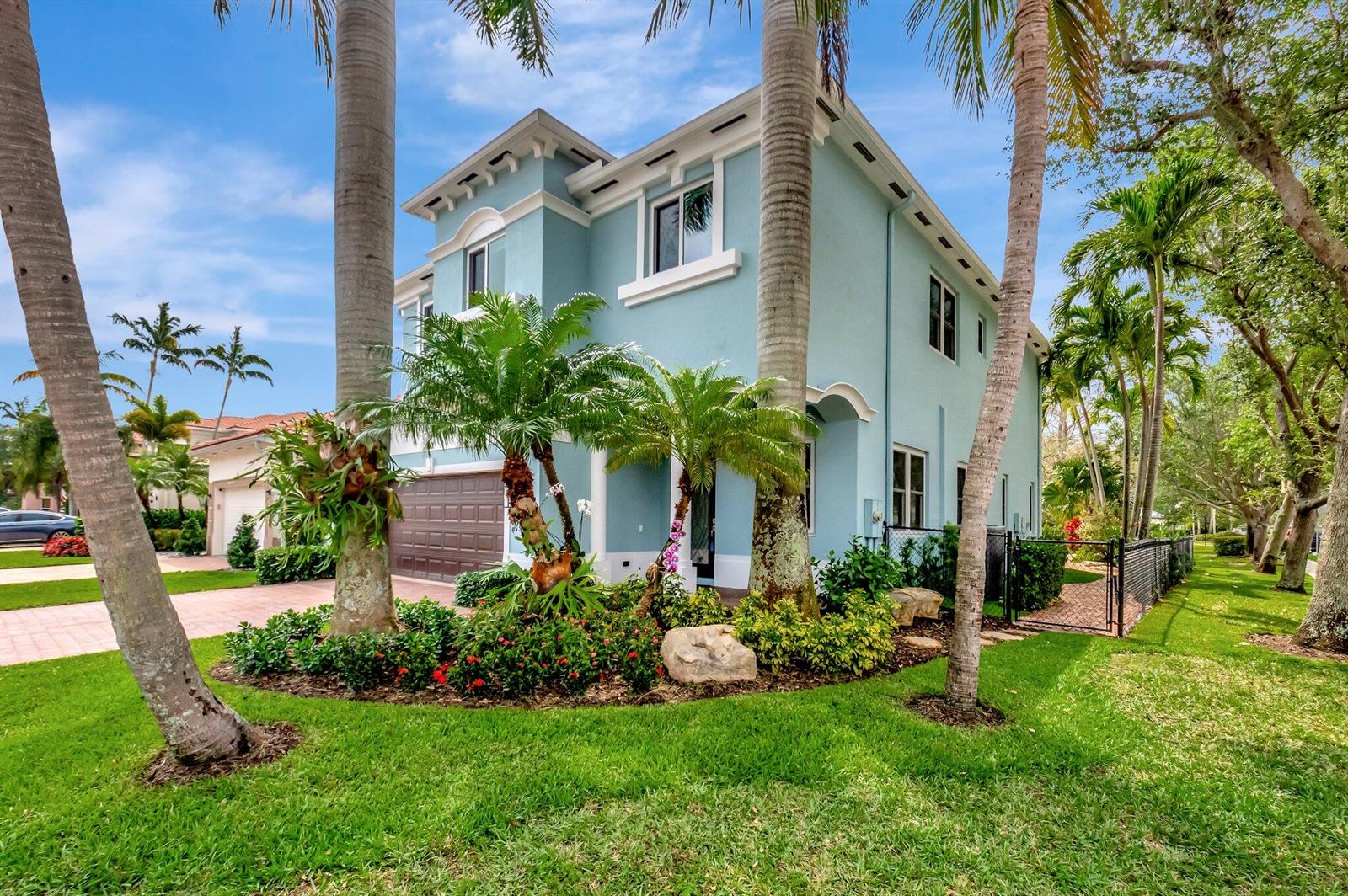 A light blue two-story house with a brown garage door and surrounding palm trees — 40 Country Lake Circle, Boynton Beach FL 33436, BOYNTON BEACH, FL
