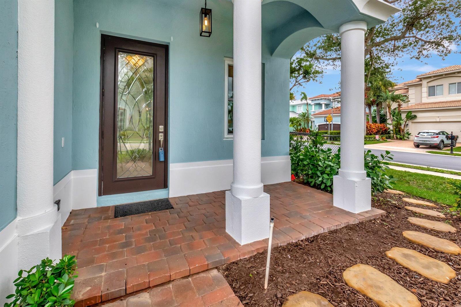 A light blue house exterior features a brick porch with white columns and a door — 40 Country Lake Circle, Boynton Beach FL 33436, BOYNTON BEACH, FL