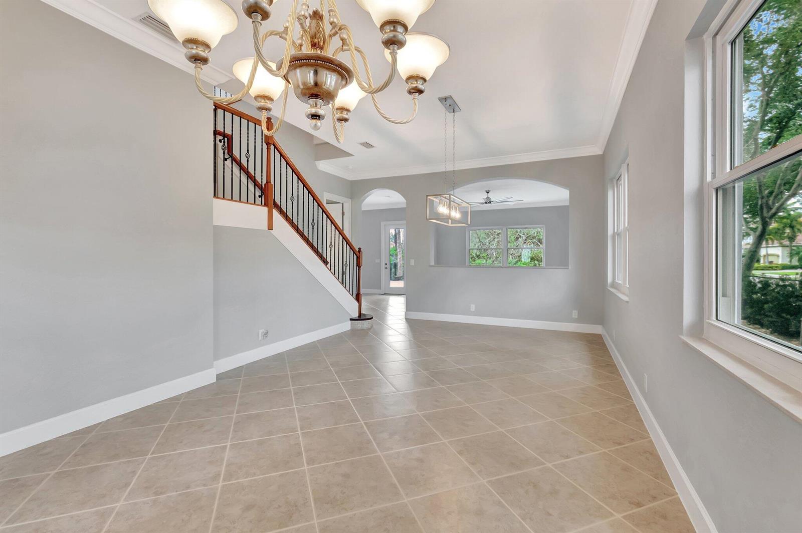 A dining area with a chandelier, tile flooring, and a staircase with a metal railing — 40 Country Lake Circle, Boynton Beach FL 33436, BOYNTON BEACH, FL