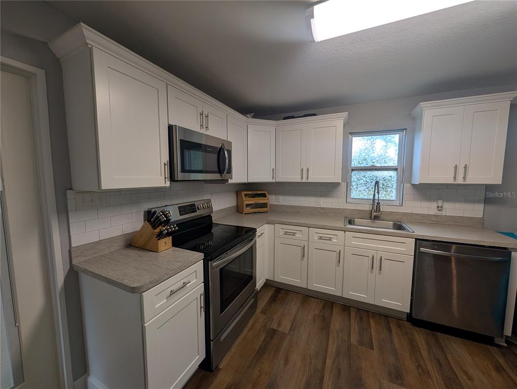 A kitchen with white cabinets, stainless steel appliances, gray countertops, and wood-look flooring — 739 CENTER STREET, WAVERLY, FL