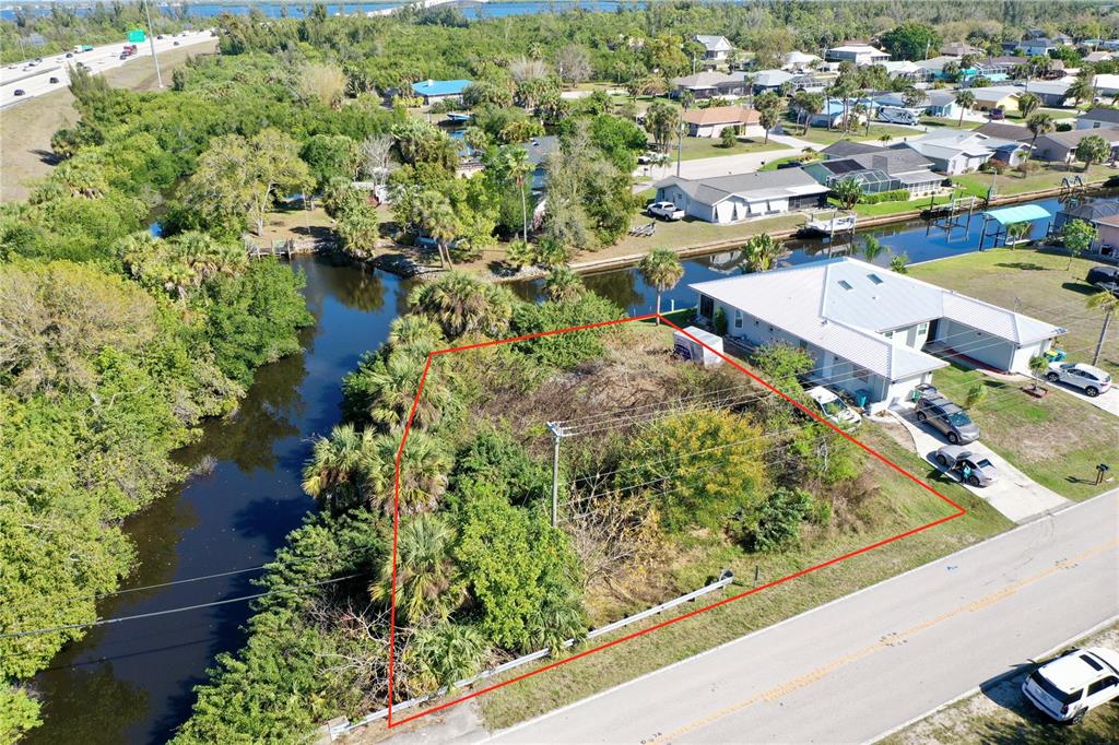 An aerial view shows a vacant, overgrown lot outlined in red next to a canal — 2803 RIVERSIDE DRIVE, PUNTA GORDA, FL