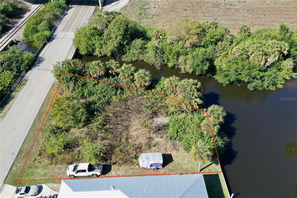 An aerial view shows a vacant, partially cleared lot bordered by a road and water — 2803 RIVERSIDE DRIVE, PUNTA GORDA, FL