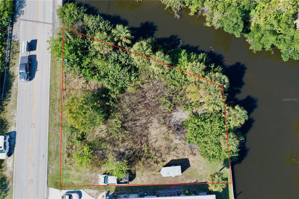 An aerial view shows a vacant, wooded lot bordered by a road and a canal — 2803 RIVERSIDE DRIVE, PUNTA GORDA, FL