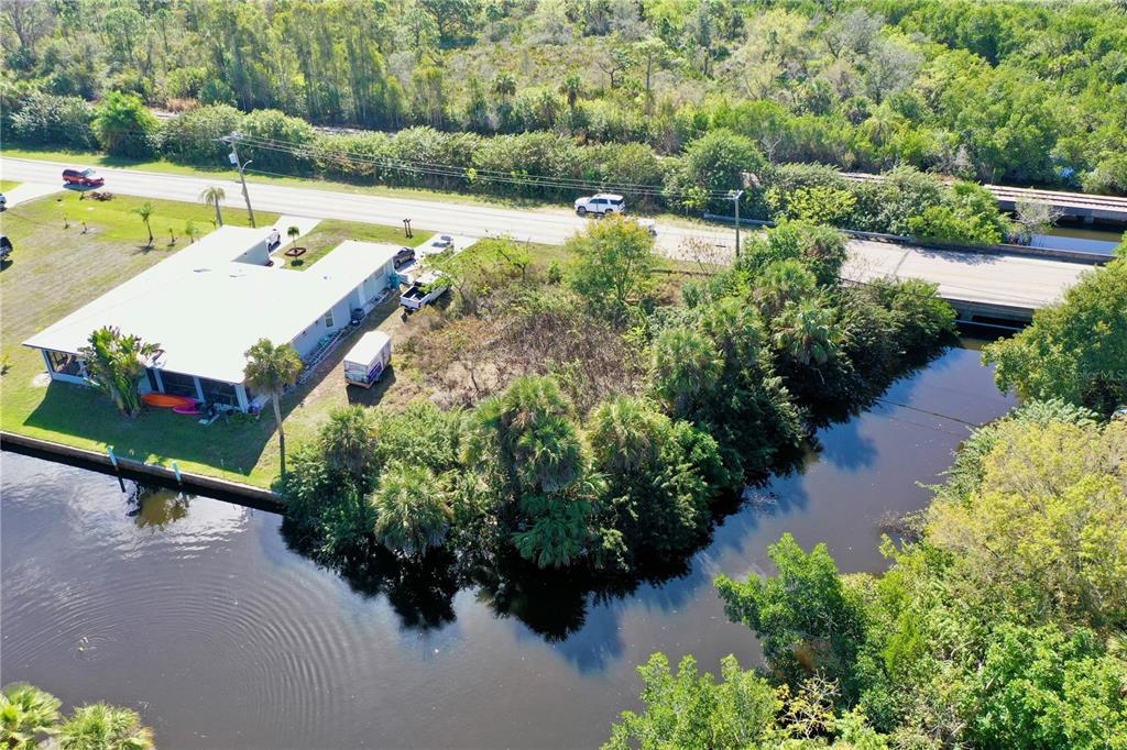 An aerial view shows a house with a metal roof situated beside a canal — 2803 RIVERSIDE DRIVE, PUNTA GORDA, FL