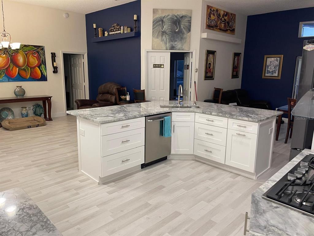 A kitchen island with white cabinets and a marble countertop sits in an open-concept room — 167 GREELEY LOOP, DAVENPORT, FL