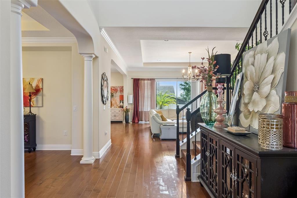 A foyer with hardwood floors leads to a living room with a staircase and columns — 4117 FOXHOUND DRIVE, CLERMONT, FL