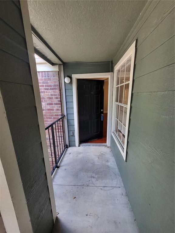 An exterior view of a covered apartment balcony with a black door and brick siding — 5064 PARK CENTRAL DRIVE UNIT 1731, ORLANDO, FL