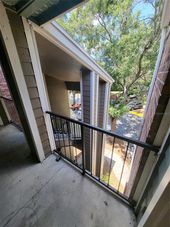 A view from a covered apartment balcony looking down toward a parking lot and trees — 5064 PARK CENTRAL DRIVE UNIT 1731, ORLANDO, FL