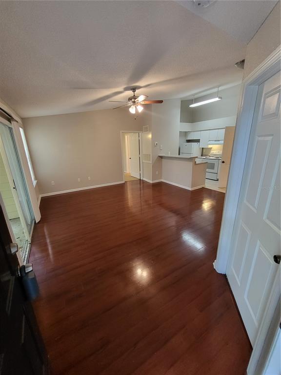 An open-concept living area features hardwood floors, a ceiling fan, and an adjacent kitchen — 5064 PARK CENTRAL DRIVE UNIT 1731, ORLANDO, FL
