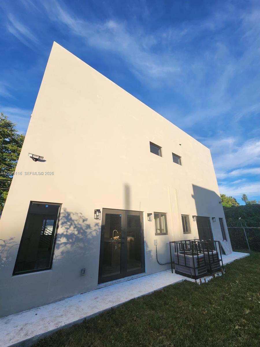 The exterior of a modern, two-story house features smooth stucco walls and dark-framed windows — 6233 NW 20th Ave # B, Miami FL 33147, MIAMI, FL
