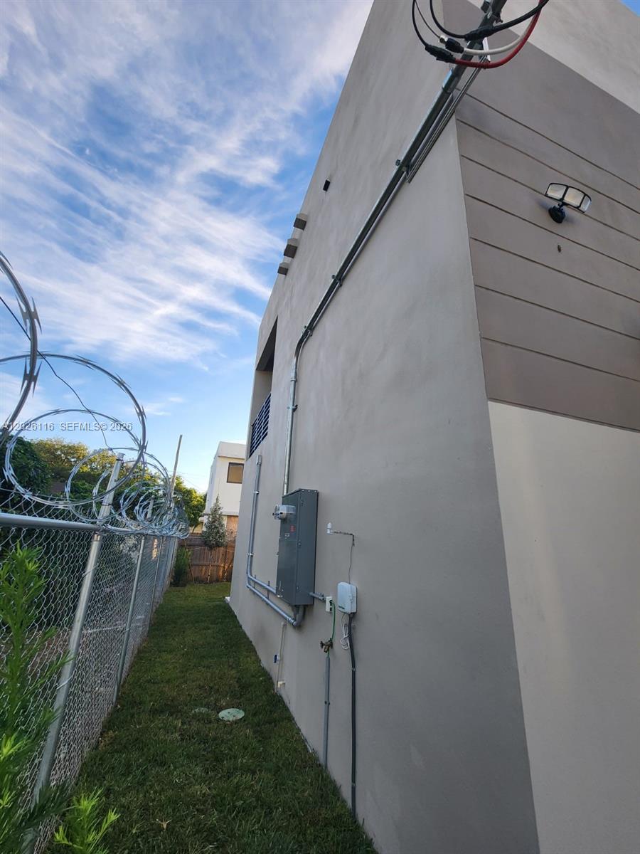 The exterior side of a modern building features a utility box, conduit, and a fence — 6233 NW 20th Ave # B, Miami FL 33147, MIAMI, FL